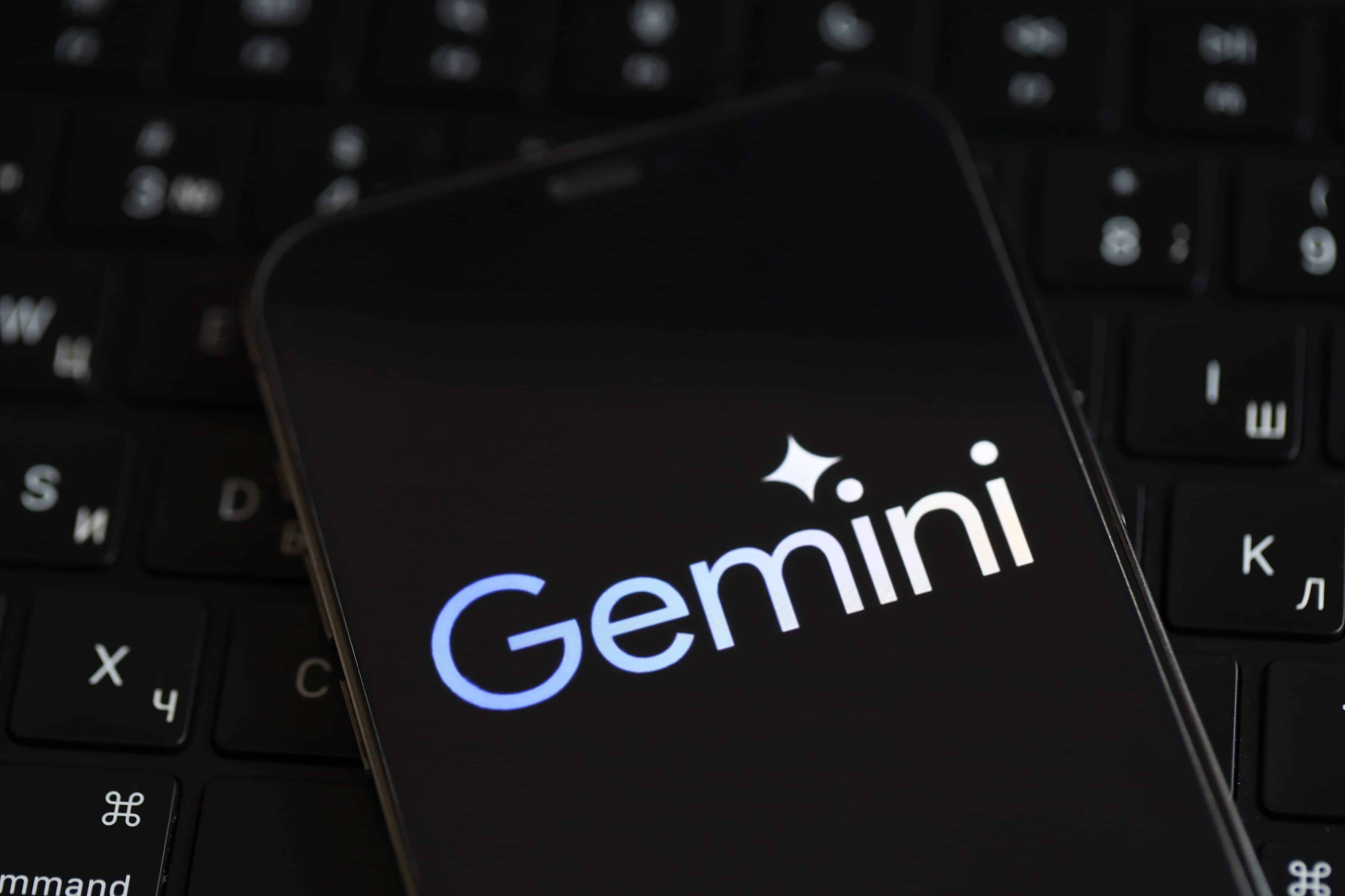 Telefone em cima de um computador com o logo do Google Gemini